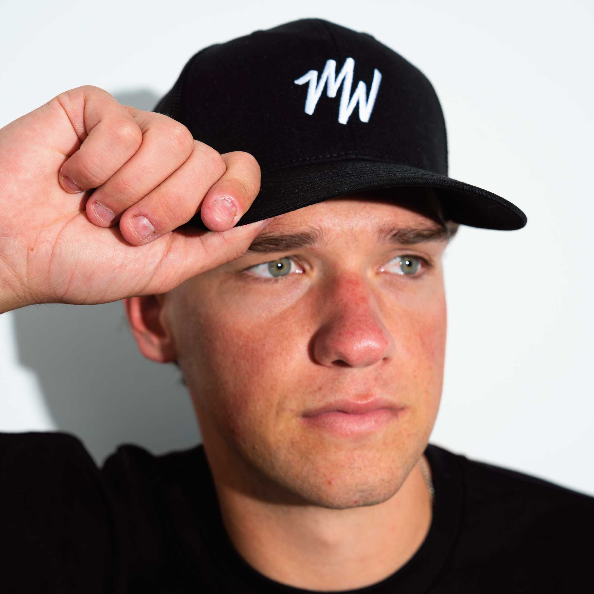 Man wearing a black cap with Midweek logo