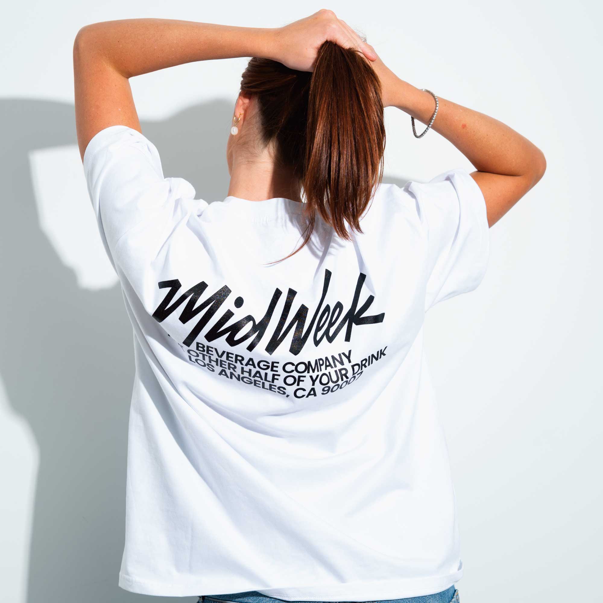 Woman wearing a white t-shirt with MidWeek branding on the back