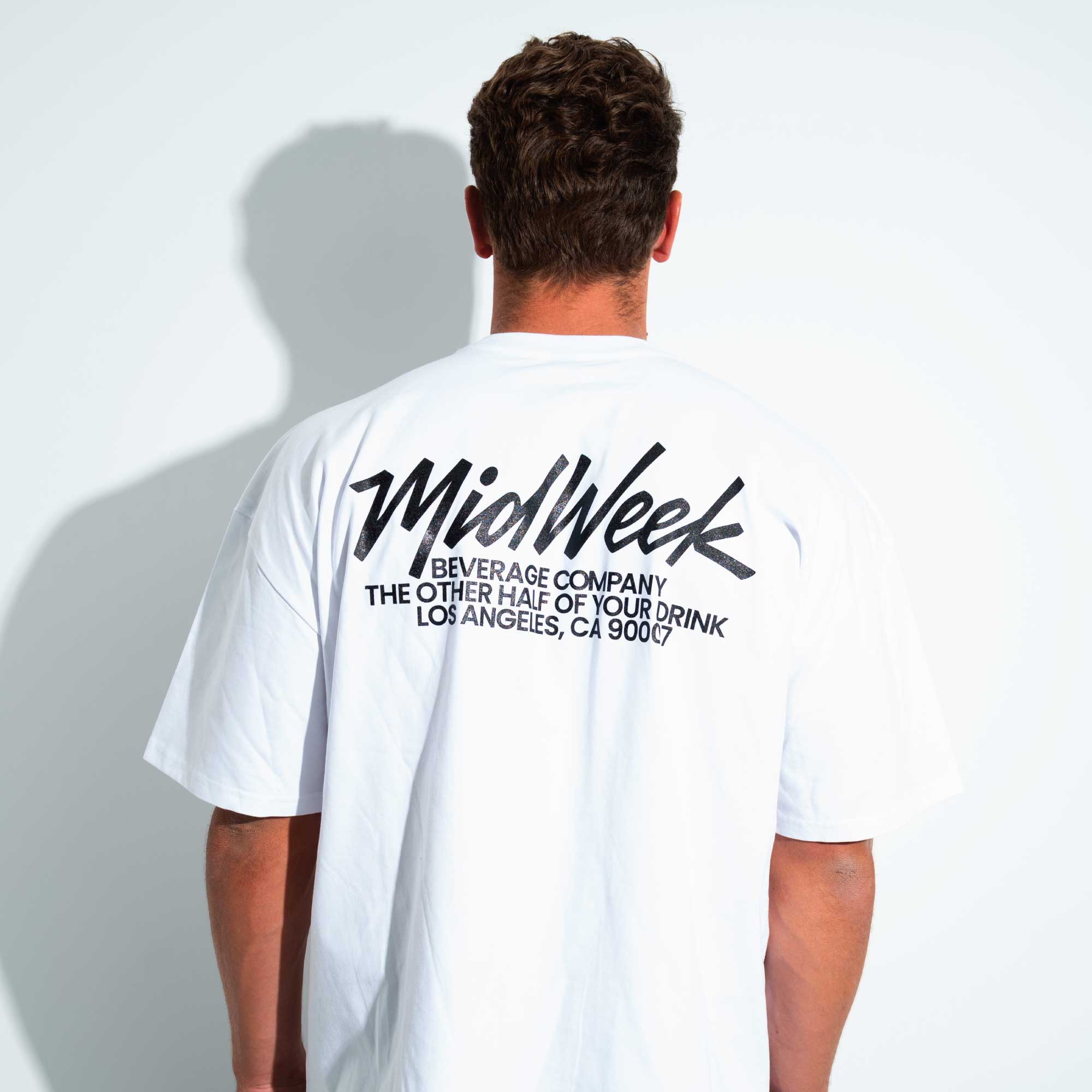 Person wearing a white t-shirt with 'Midweek' branding on the back 